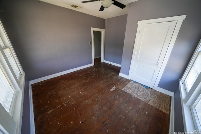 unfurnished bedroom with multiple windows, dark hardwood / wood-style floors, ceiling fan, and a closet