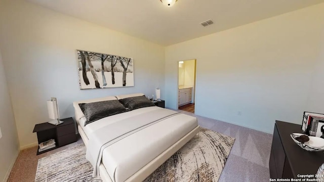 bedroom with connected bathroom and light colored carpet