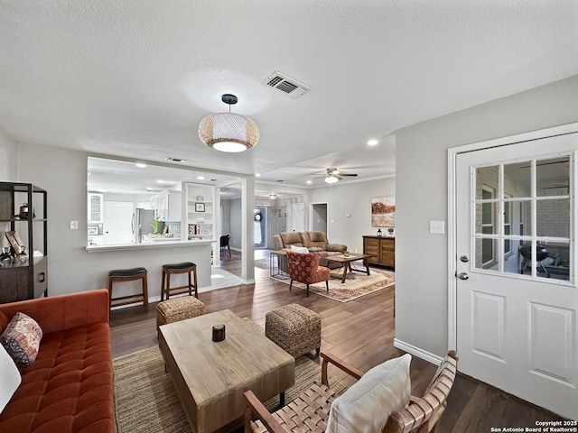 living room with dark wood-style floors, recessed lighting, visible vents, a textured ceiling, and baseboards