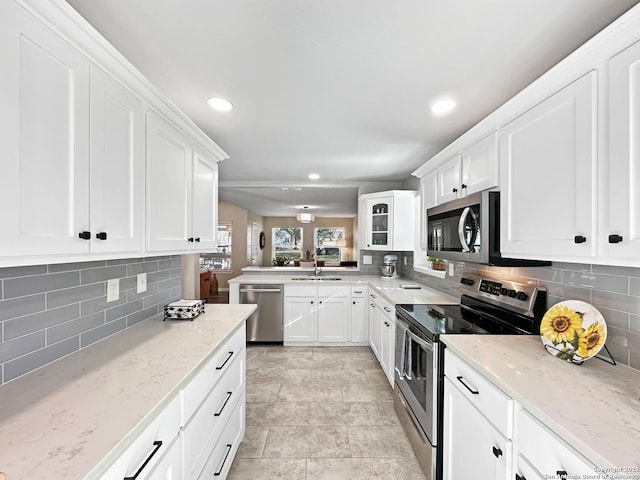 kitchen featuring light stone counters, tasteful backsplash, appliances with stainless steel finishes, white cabinets, and a sink