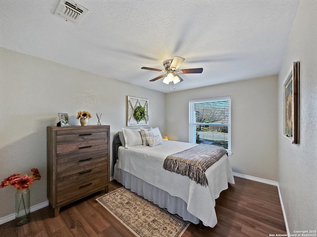 bedroom featuring dark wood-style flooring, visible vents, a textured ceiling, and baseboards