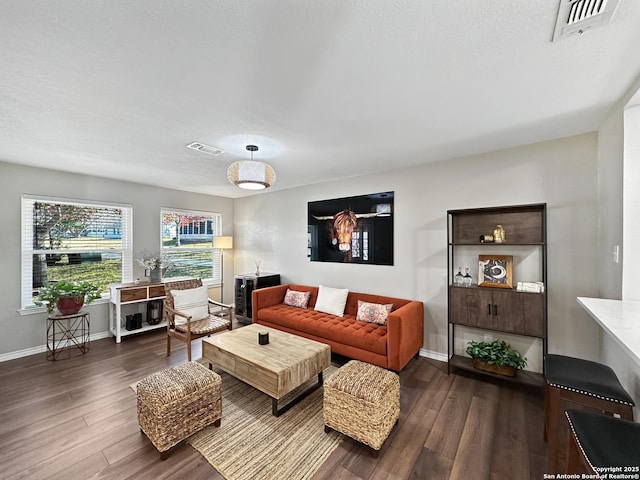 living area with visible vents, baseboards, and wood finished floors