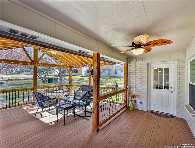 wooden terrace with ceiling fan and an outdoor hangout area