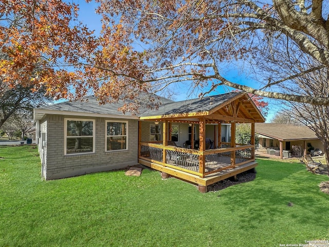 rear view of house with brick siding, a lawn, and a deck