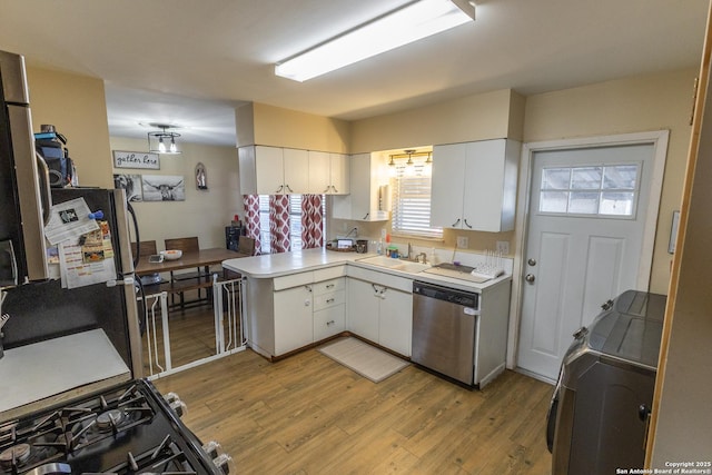 kitchen with appliances with stainless steel finishes, kitchen peninsula, and white cabinets