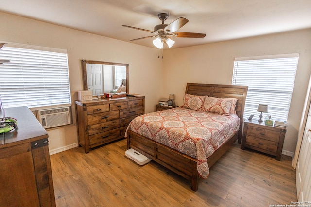 bedroom featuring hardwood / wood-style floors, a wall unit AC, and ceiling fan