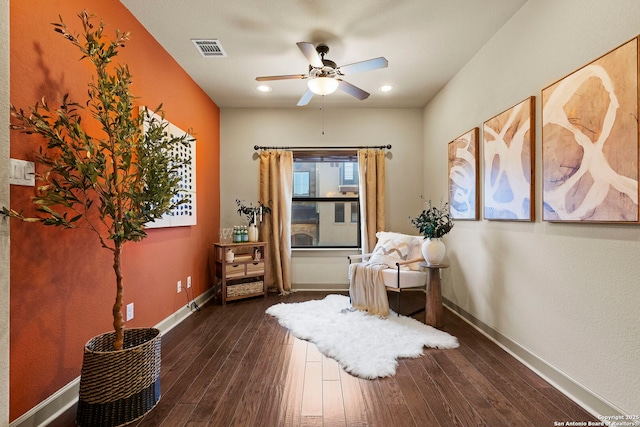 sitting room with dark wood-type flooring and ceiling fan