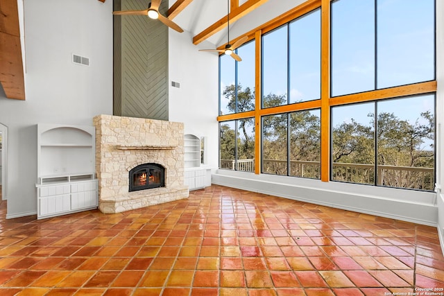 unfurnished living room featuring beamed ceiling, a healthy amount of sunlight, a fireplace, and high vaulted ceiling