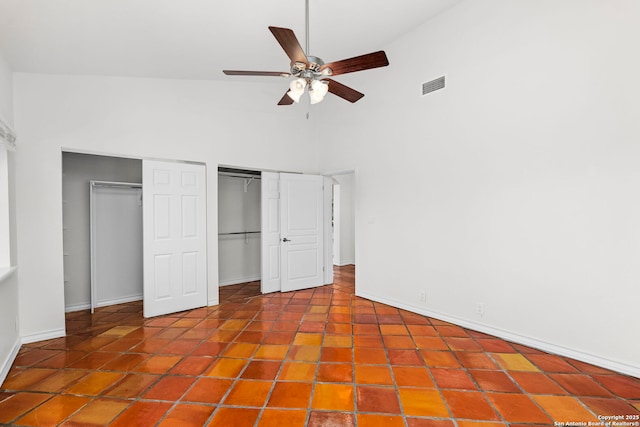 unfurnished bedroom featuring ceiling fan, high vaulted ceiling, and two closets