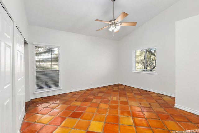 tiled empty room featuring ceiling fan and lofted ceiling