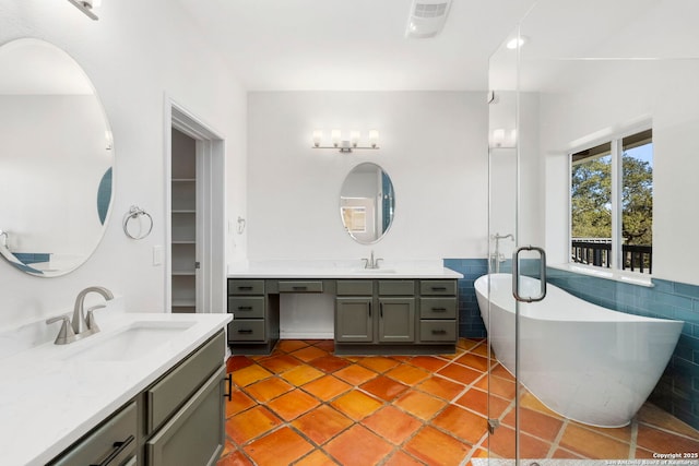 bathroom with vanity, tile patterned floors, tile walls, and a bathing tub