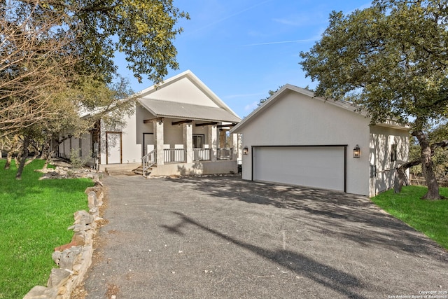 view of front of property with a garage, covered porch, and a front lawn