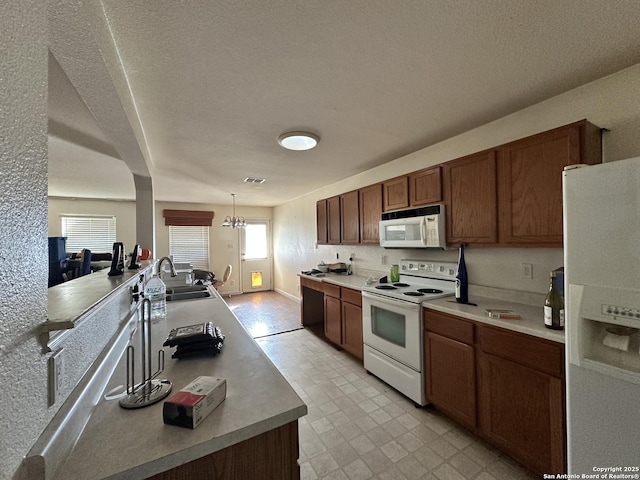 kitchen with pendant lighting, sink, white appliances, and a healthy amount of sunlight