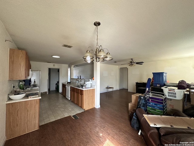 kitchen featuring sink, light hardwood / wood-style flooring, dishwasher, hanging light fixtures, and a textured ceiling