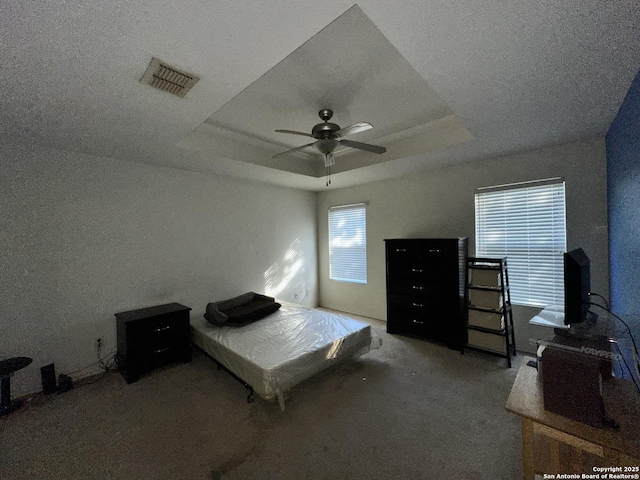 carpeted bedroom featuring ceiling fan and a raised ceiling