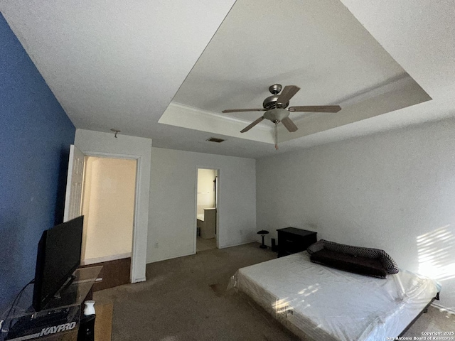 carpeted bedroom with ceiling fan and a raised ceiling