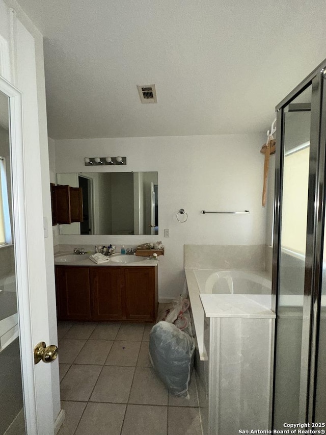 bathroom featuring vanity, a washtub, and tile patterned floors