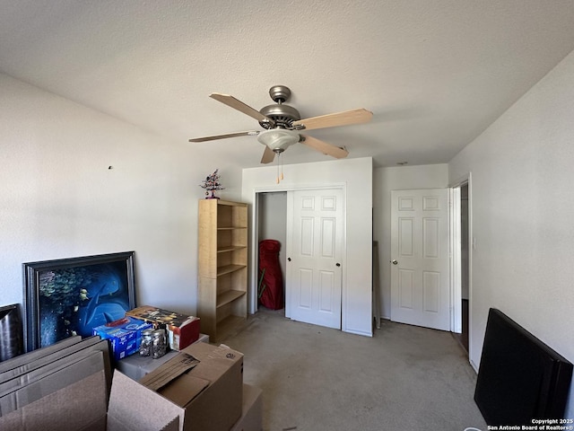 carpeted bedroom with a textured ceiling, ceiling fan, and a closet