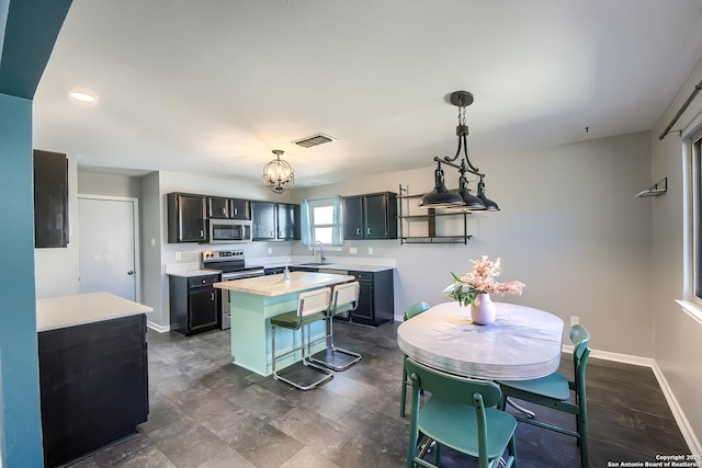 kitchen with hanging light fixtures, sink, stainless steel appliances, and a center island