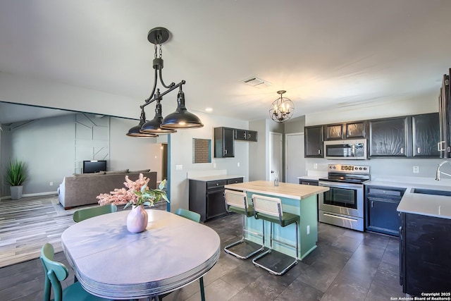 kitchen with dark brown cabinetry, sink, decorative light fixtures, a center island, and stainless steel appliances