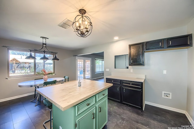 kitchen featuring green cabinets, hanging light fixtures, a center island, a healthy amount of sunlight, and wood counters