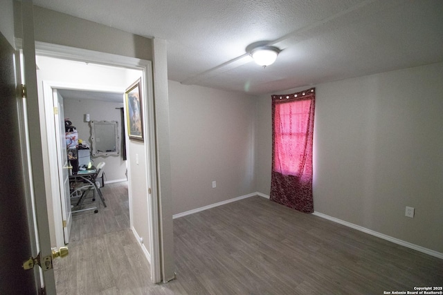 spare room featuring wood-type flooring and a textured ceiling