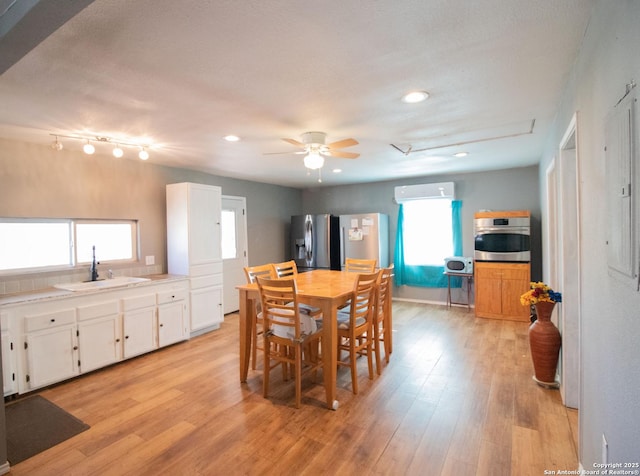 dining room with ceiling fan, sink, light hardwood / wood-style flooring, and an AC wall unit