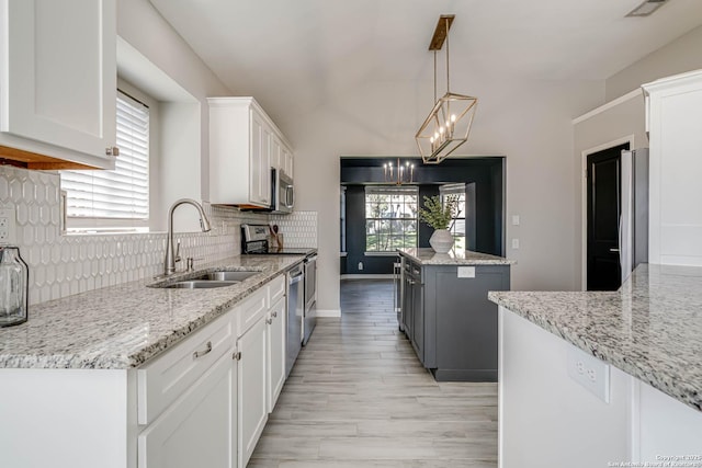 kitchen featuring white cabinetry, stainless steel appliances, light stone countertops, and a kitchen island