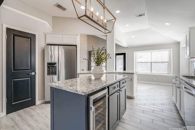 kitchen featuring lofted ceiling, stainless steel appliances, a center island, wine cooler, and white cabinets