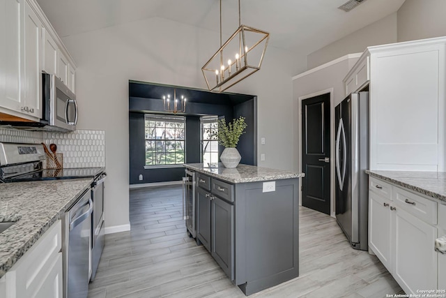 kitchen with white cabinetry, decorative light fixtures, light stone countertops, and appliances with stainless steel finishes