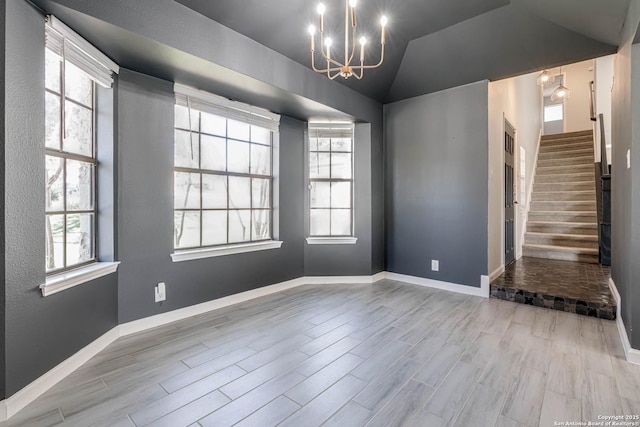 empty room featuring lofted ceiling, plenty of natural light, and a chandelier