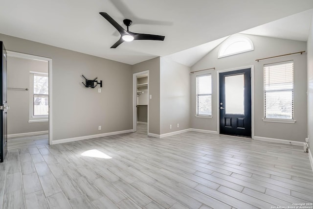 entrance foyer featuring ceiling fan, a wealth of natural light, vaulted ceiling, and light wood-type flooring