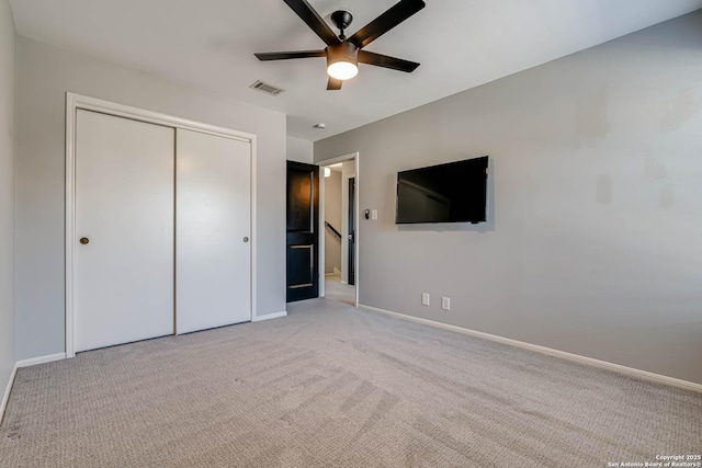 unfurnished bedroom featuring light carpet, ceiling fan, and a closet