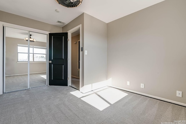 unfurnished bedroom with light colored carpet and a closet