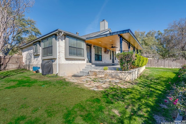 rear view of property with a lawn and ceiling fan