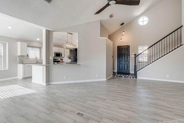 unfurnished living room featuring sink, vaulted ceiling, and a healthy amount of sunlight