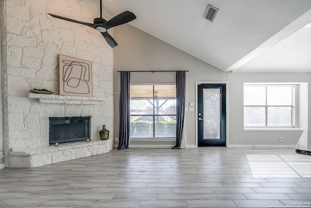 unfurnished living room with ceiling fan, a stone fireplace, and vaulted ceiling