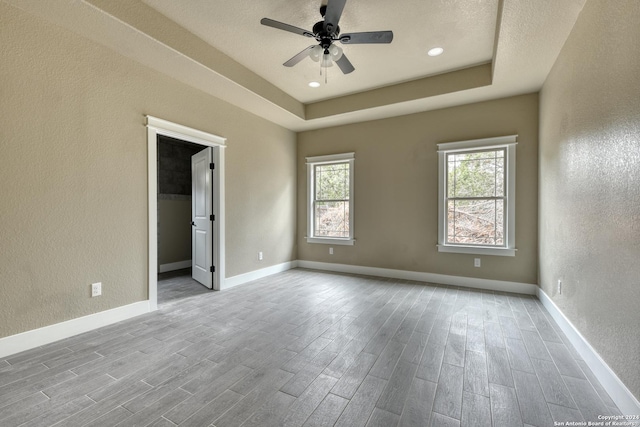 unfurnished room featuring a textured ceiling, a raised ceiling, and ceiling fan