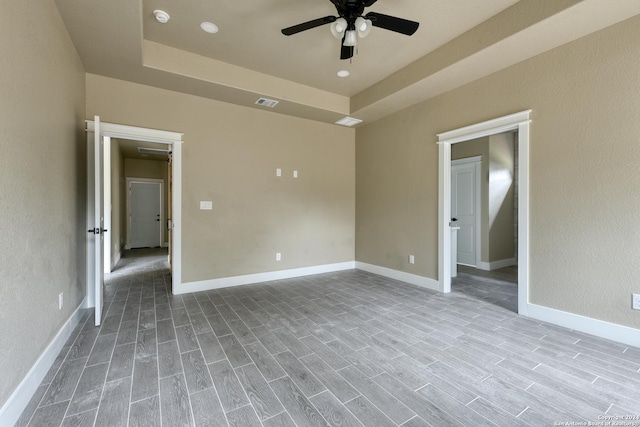 spare room featuring ceiling fan, a raised ceiling, and light hardwood / wood-style flooring