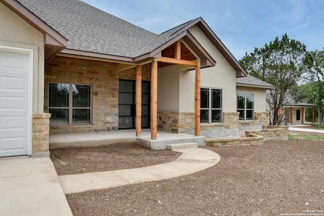 rear view of property featuring a garage and covered porch