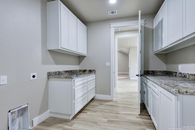 laundry room featuring cabinets, hookup for an electric dryer, and light hardwood / wood-style flooring