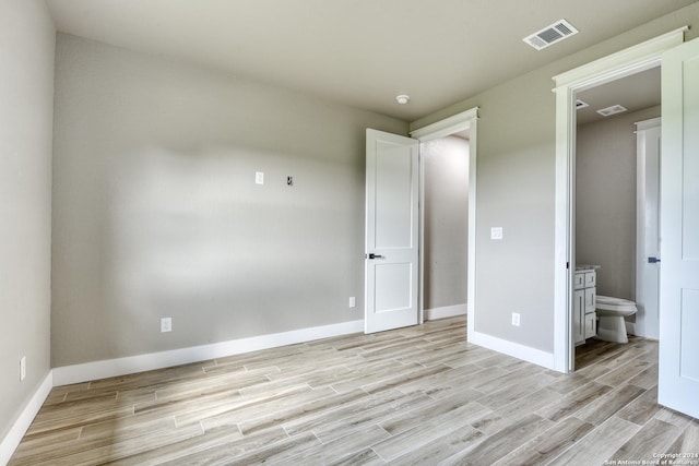 unfurnished bedroom featuring connected bathroom and light hardwood / wood-style floors