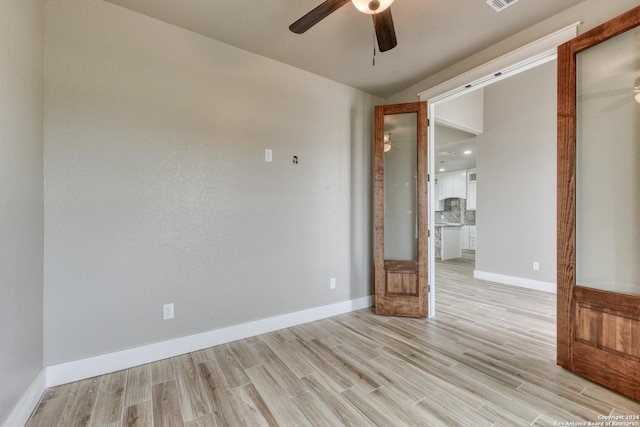 empty room with a barn door, ceiling fan, and light hardwood / wood-style floors