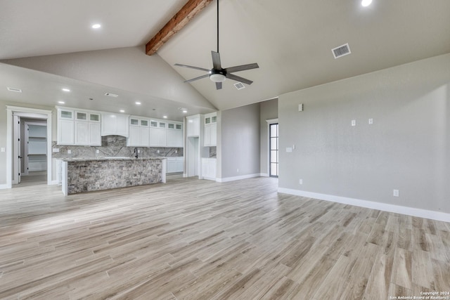 unfurnished living room with ceiling fan, high vaulted ceiling, beamed ceiling, and light wood-type flooring