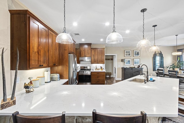 kitchen featuring pendant lighting, stainless steel appliances, a kitchen bar, and sink