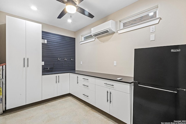 kitchen with black refrigerator, white cabinetry, ceiling fan, and a wall unit AC