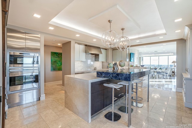 kitchen with a raised ceiling, premium range hood, a large island, and backsplash