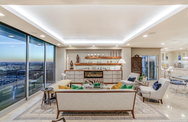 living room with floor to ceiling windows and a raised ceiling