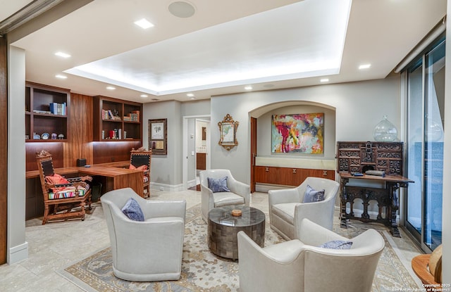 sitting room with a tray ceiling and built in shelves