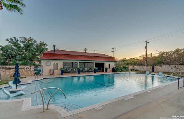 pool at dusk with a patio area